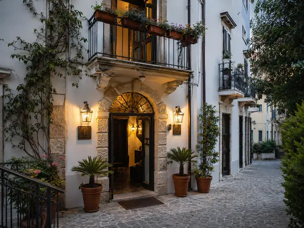 Ingresso di un piccolo hotel o bed and breakfast in un edificio di charme, con facciata curata, luci calde e atmosfera accogliente.
